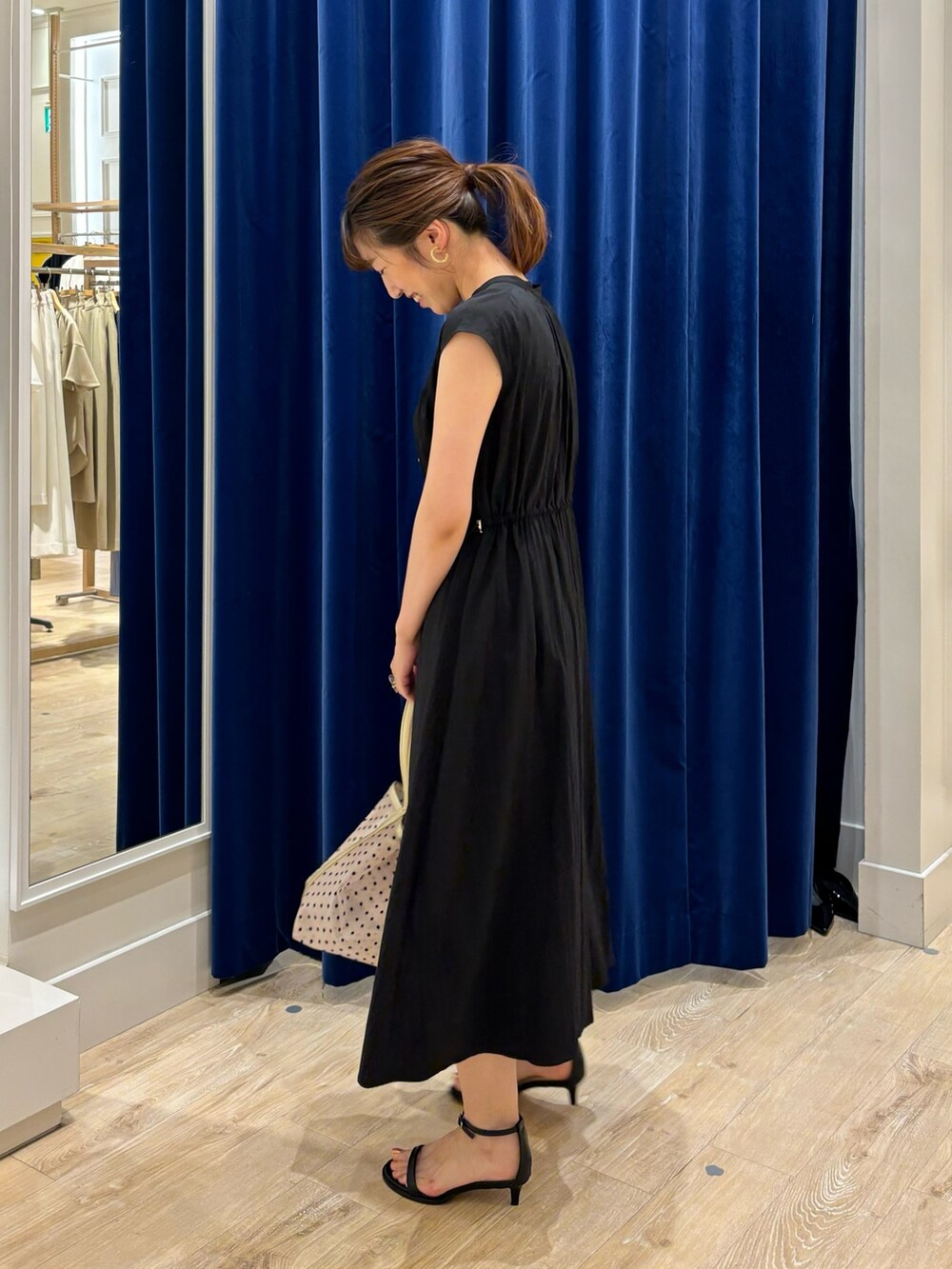 ブラック系のワンピース、ベージュ系のトートバッグ、ブラック系のサンダルを着用したレディースの春コーディネートの5枚目の写真