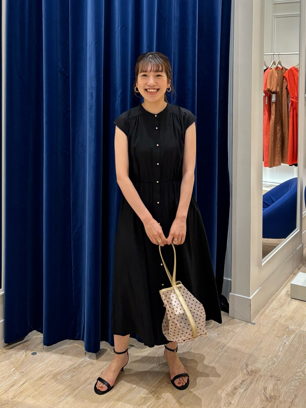 ブラック系のワンピース、ベージュ系のトートバッグ、ブラック系のサンダルを着用したレディースの春コーディネートの3枚目の写真