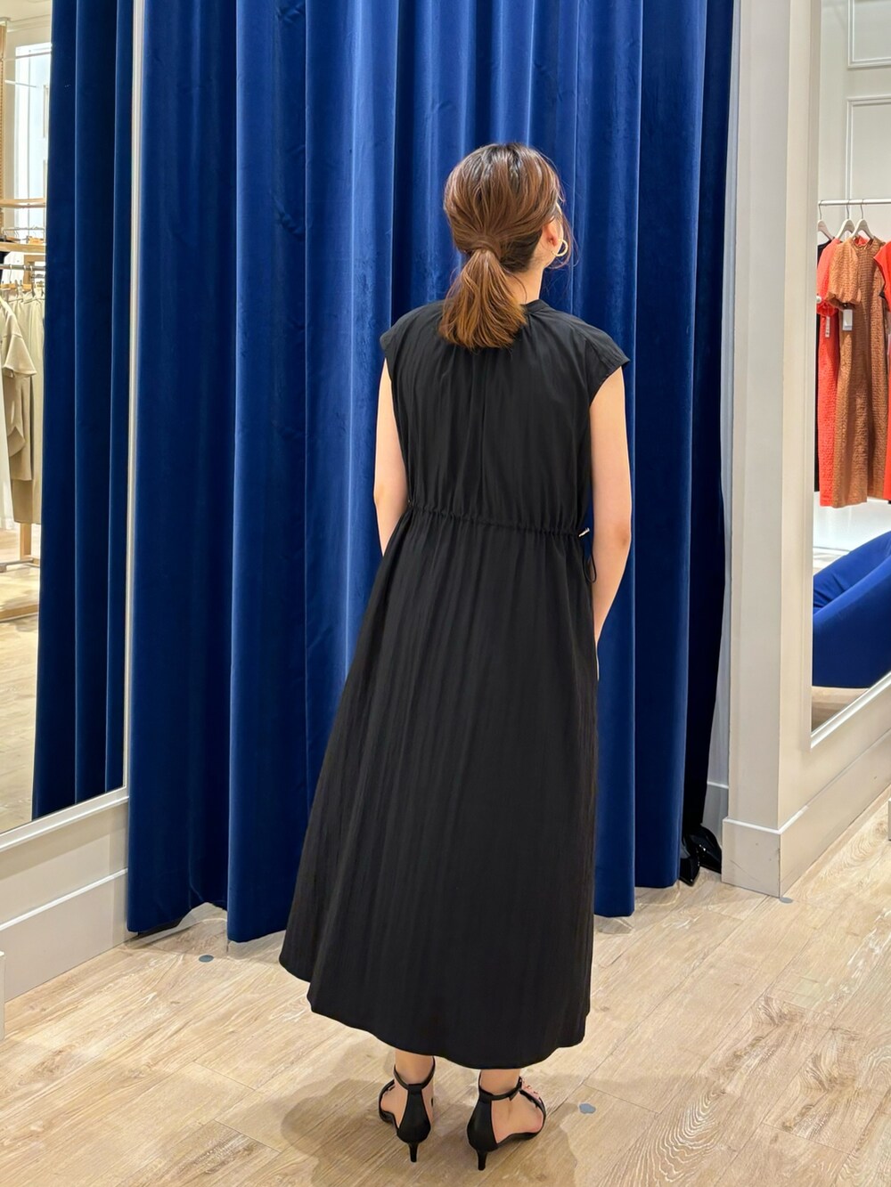 ブラック系のワンピース、ベージュ系のトートバッグ、ブラック系のサンダルを着用したレディースの春コーディネートの6枚目の写真