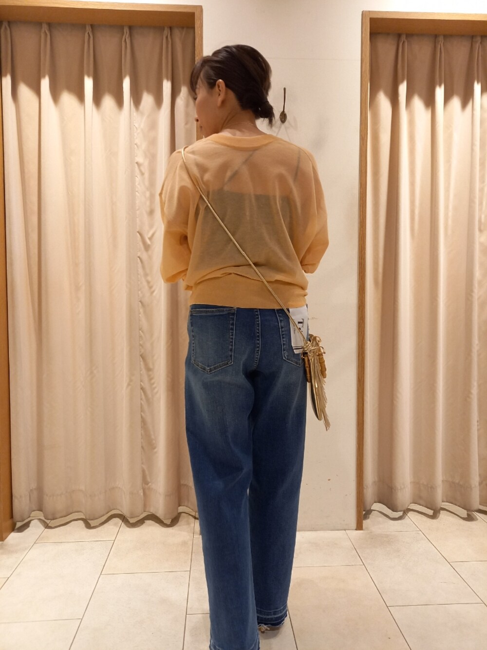 オレンジ系のカーディガン/ボレロ、ブルー系のデニムパンツを着用したレディースの春コーディネートの3枚目の写真