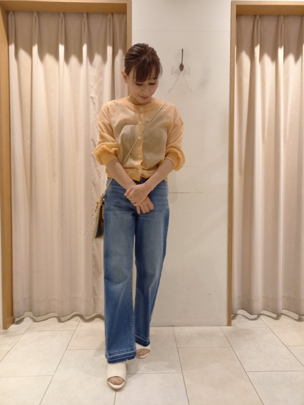 オレンジ系のカーディガン/ボレロ、ブルー系のデニムパンツを着用したレディースの春コーディネートの2枚目の写真