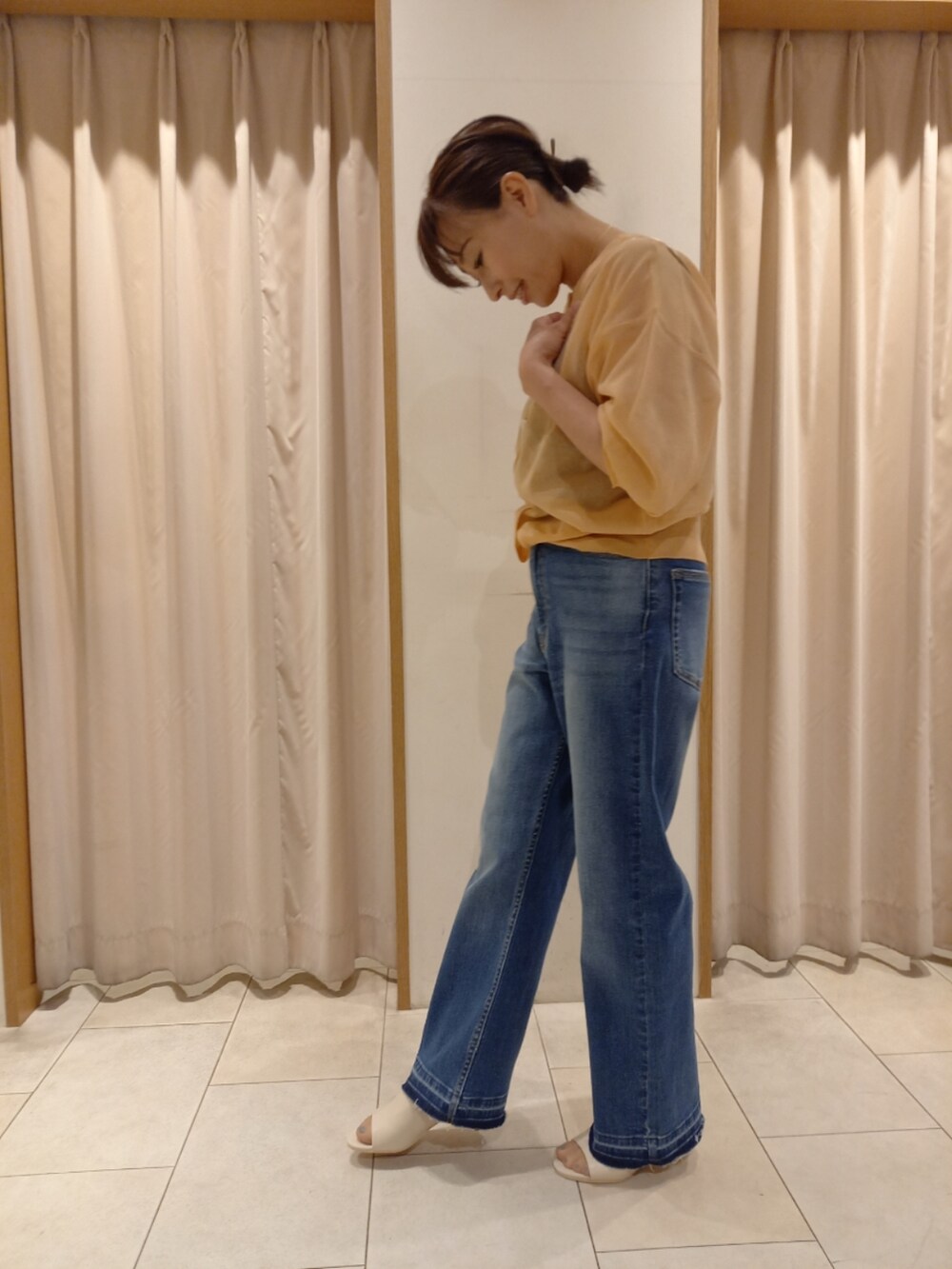 オレンジ系のカーディガン/ボレロ、ブルー系のデニムパンツを着用したレディースの春コーディネートの4枚目の写真