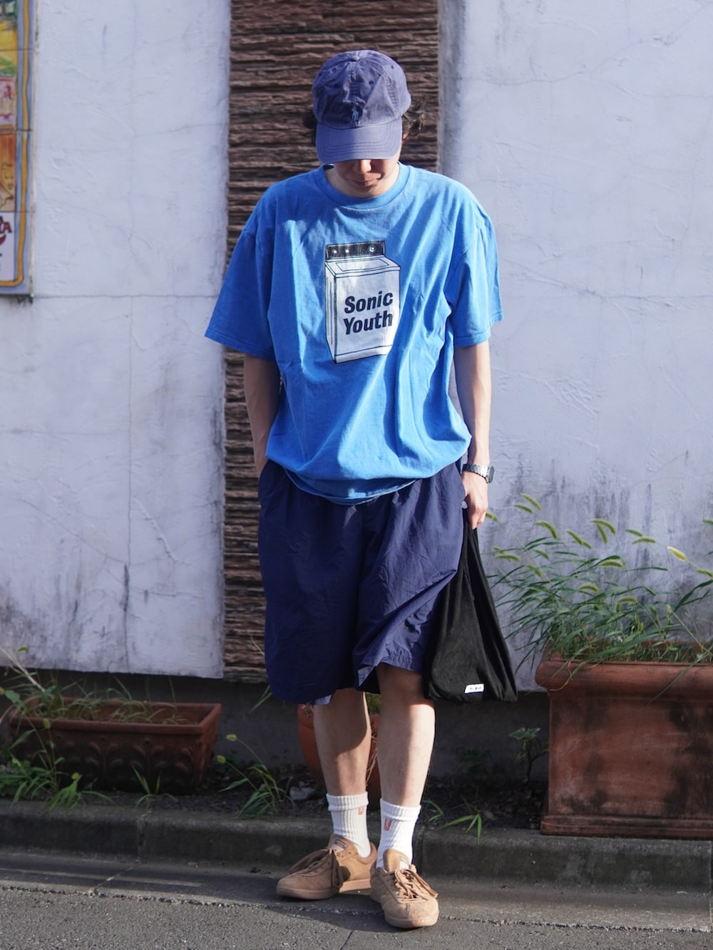ブラック系のハンドバッグ、ブラウン系のスニーカー、ブルー系のTシャツ/カットソーを着用したメンズの秋コーディネートの2枚目の写真