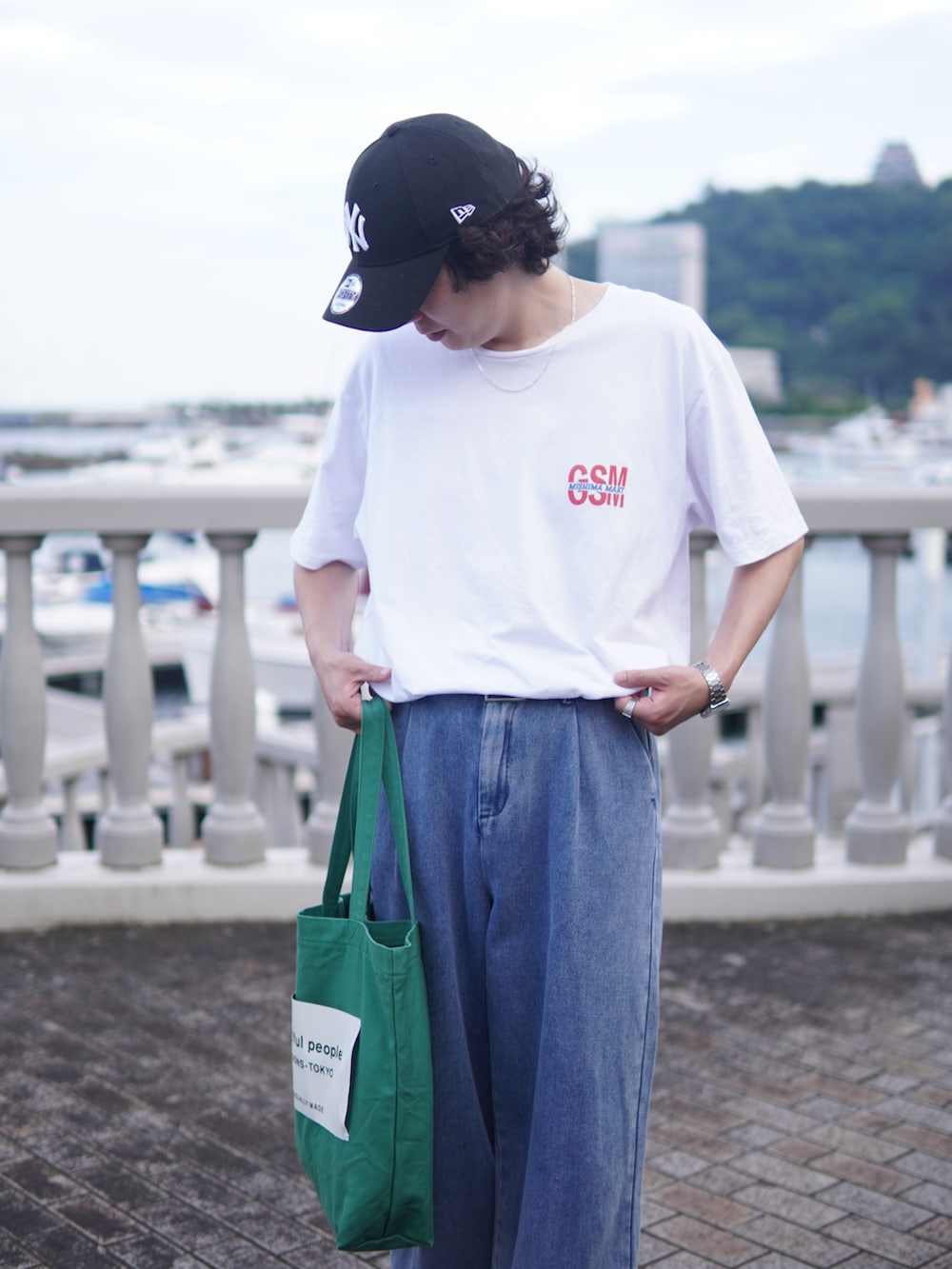 ホワイト系のTシャツ/カットソー、グリーン系のトートバッグ、ブルー系のデニムパンツを着用したメンズの夏コーディネートの3枚目の写真