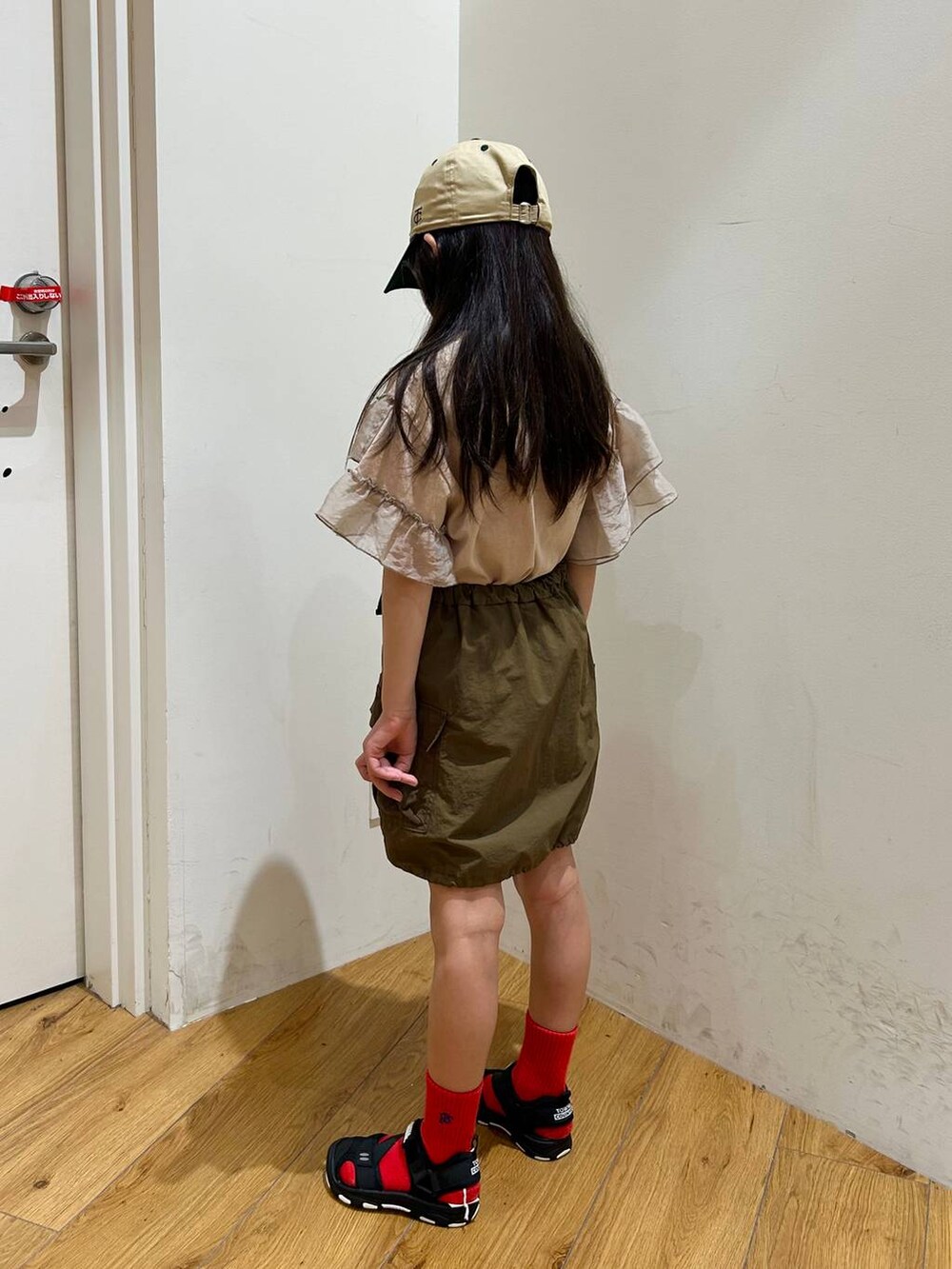 ブラック系のサンダル、グリーン系のスカート、ベージュ系のTシャツ/カットソーを着用したキッズの春コーディネートの2枚目の写真