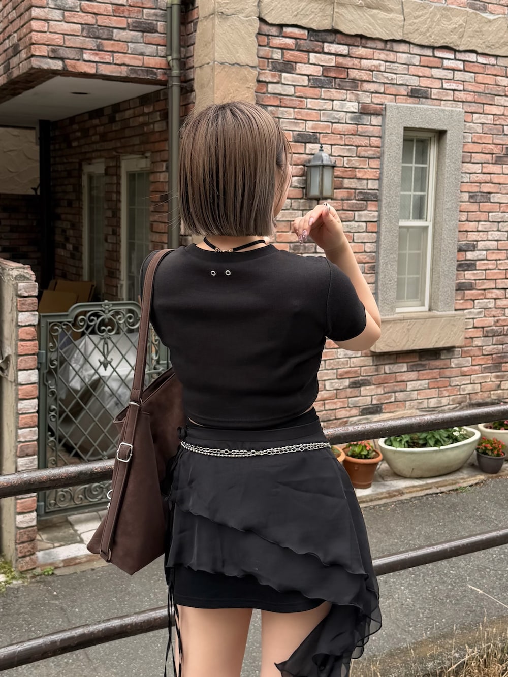 ブラウン系のショルダーバッグ、ブラック系のスカート、ブラック系のTシャツ/カットソーを着用したレディースの夏コーディネートの3枚目の写真