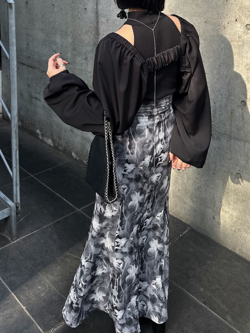 グレー系のスカート、ブラック系のカーディガン/ボレロ、ブラック系のキャミソールを着用したレディースの春コーディネートの2枚目の写真