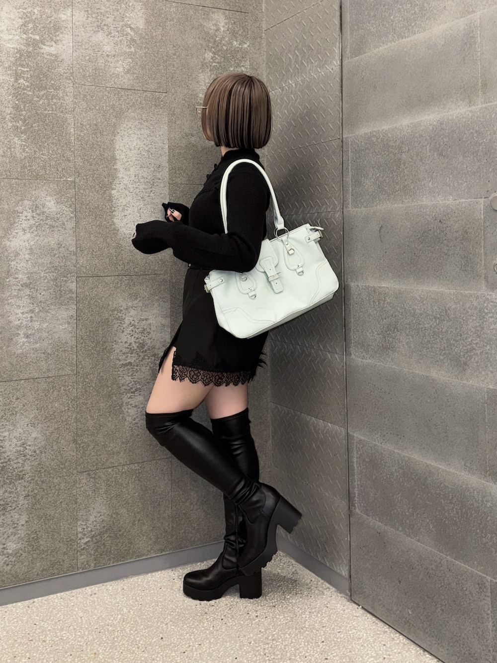 ブラック系のスカート、ブラック系のニット/セーター、グリーン系のボストンバッグを着用したレディースの秋コーディネートの2枚目の写真