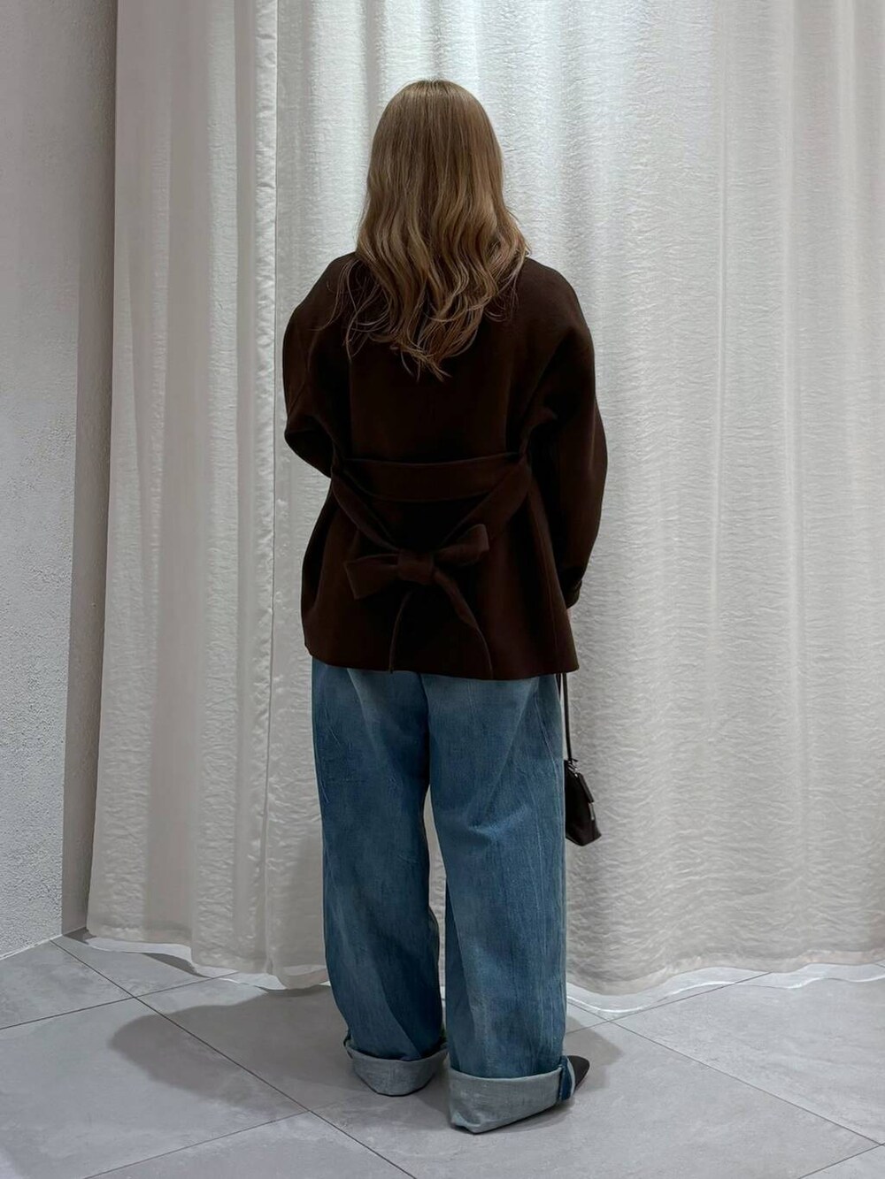 ブラウン系のノーカラージャケット、ホワイト系のTシャツ/カットソー、ブルー系のデニムパンツを着用したレディースの秋コーディネートの2枚目の写真