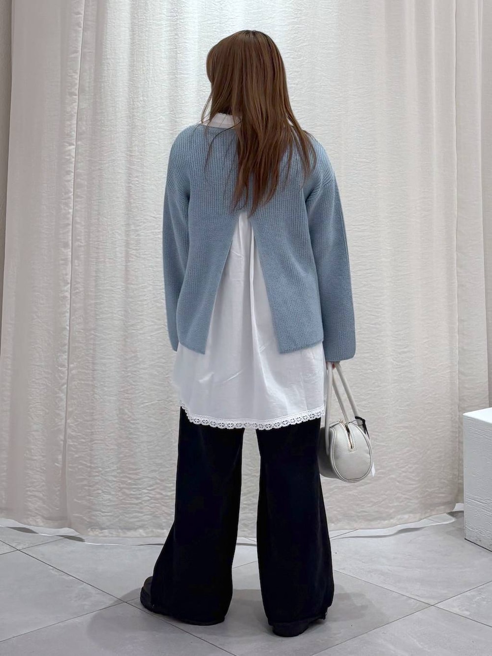 ブラック系のデニムパンツ、ブラック系のブーツ、ホワイト系のシャツ/ブラウスを着用したレディースの冬コーディネートの2枚目の写真