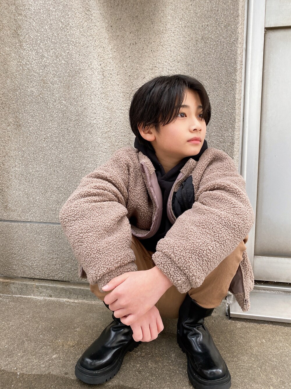 ブラウン系のブルゾン、ブラック系のパーカー、ベージュ系のその他パンツを着用したキッズの冬コーディネートの2枚目の写真