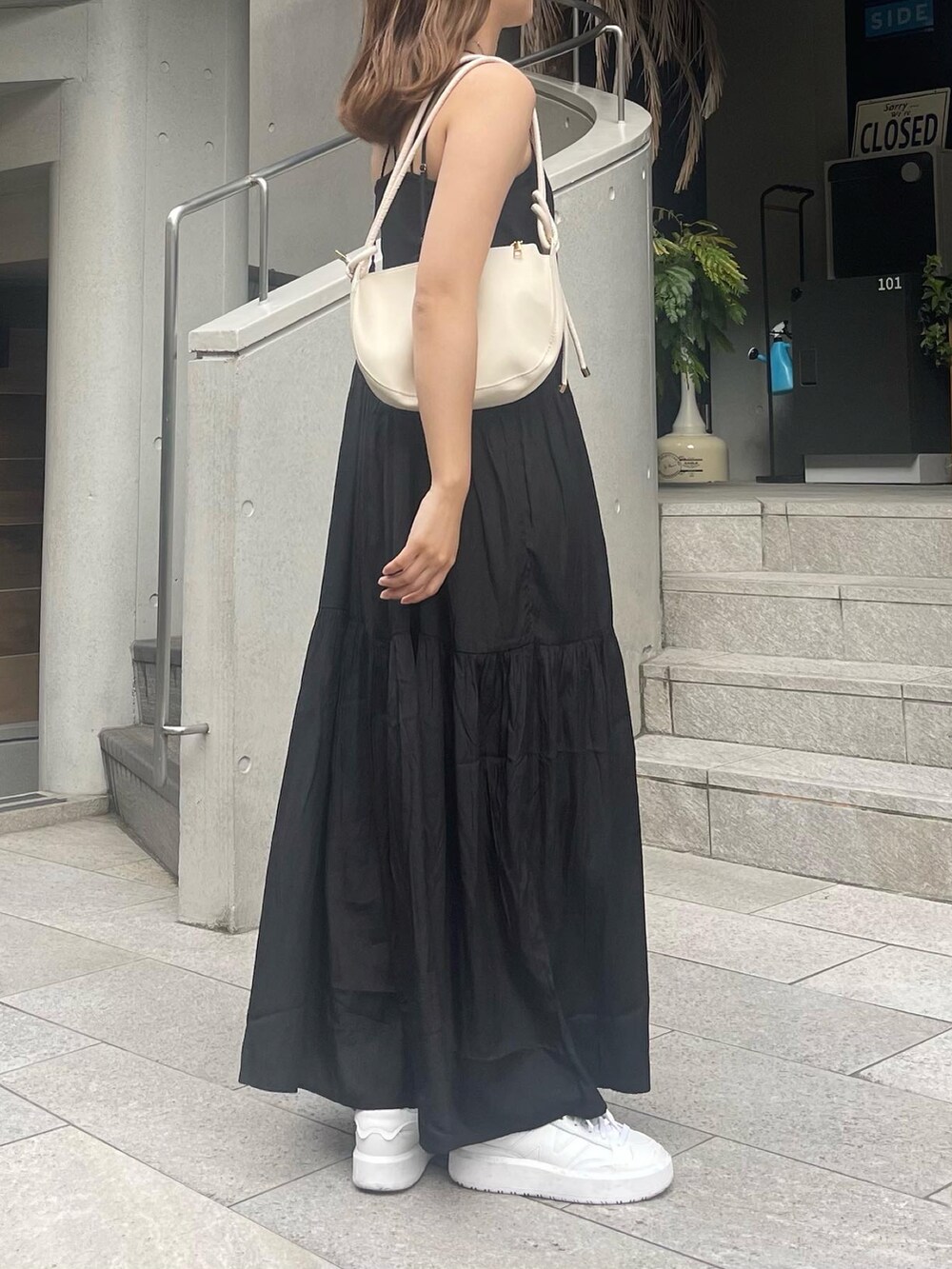 ブラック系のワンピース、ブルー系のキャップを着用したレディースの夏コーディネートの2枚目の写真