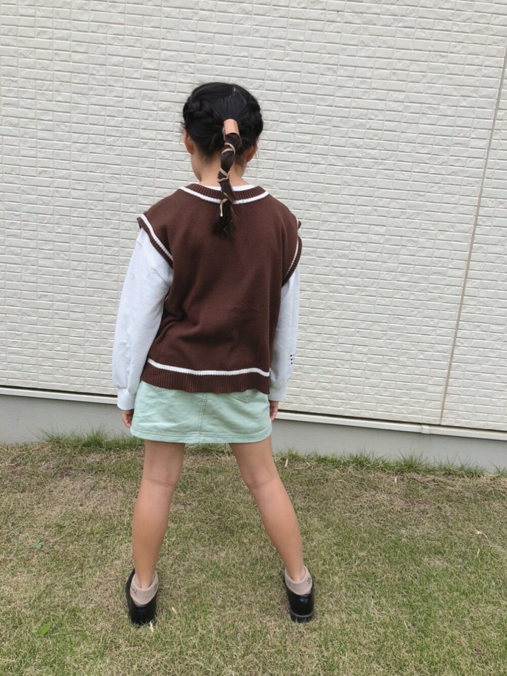 グリーン系のスカート、ブラウン系のベストを着用したキッズの秋コーディネートの3枚目の写真
