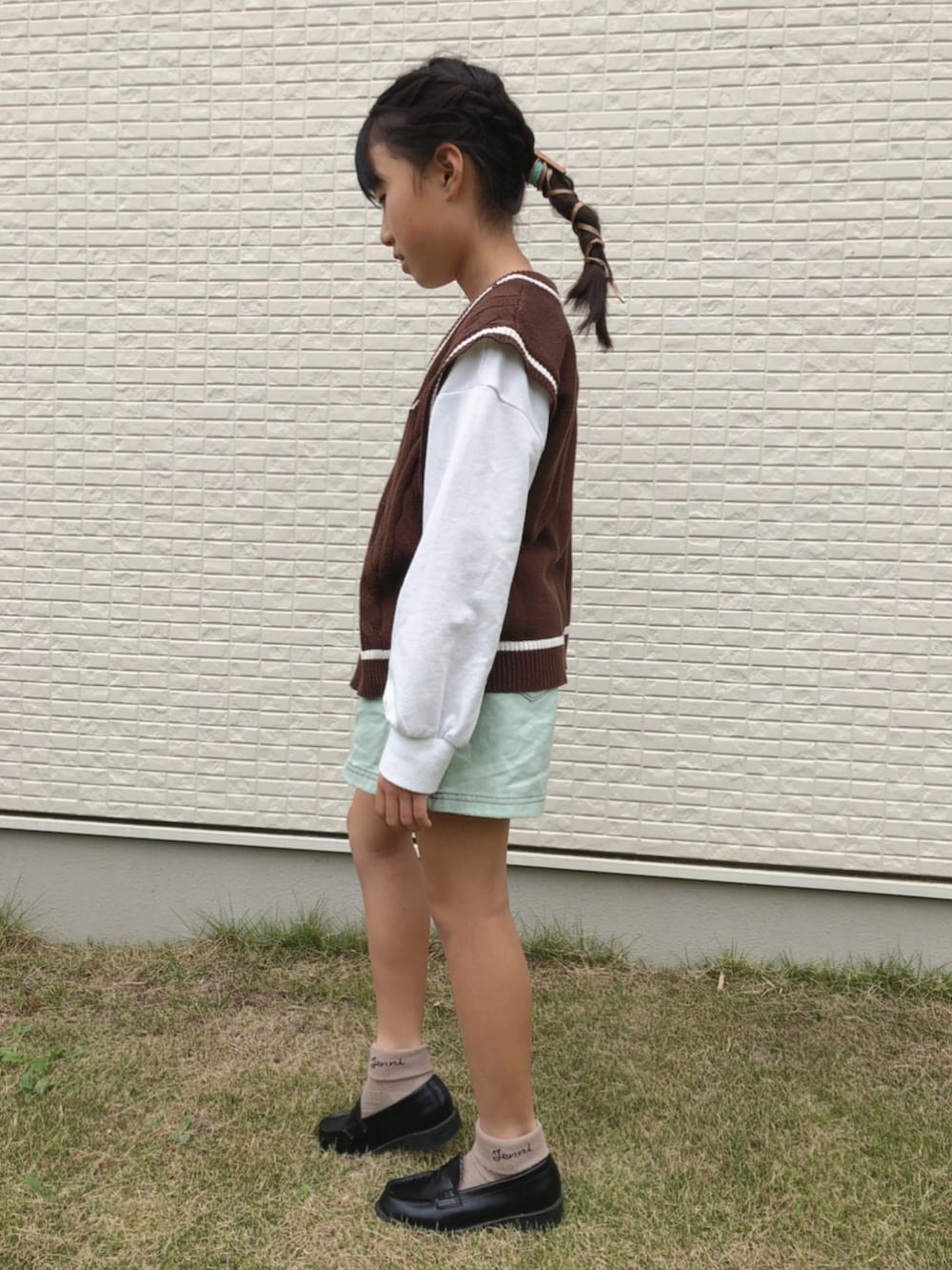 グリーン系のスカート、ブラウン系のベストを着用したキッズの秋コーディネートの2枚目の写真