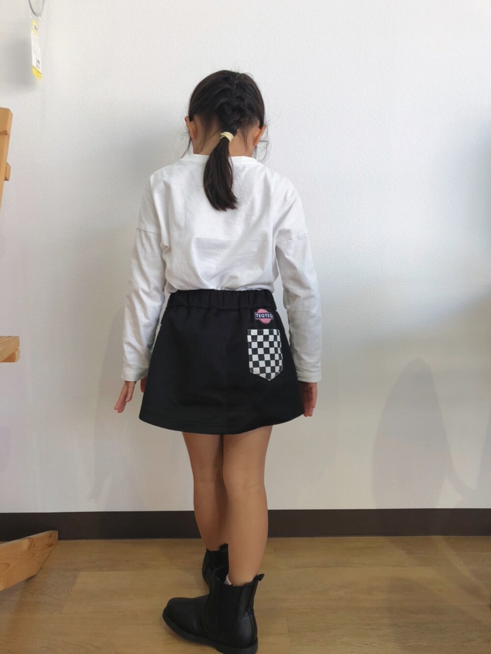ホワイト系のTシャツ/カットソー、ブラック系のスカート、ブラック系のブーツを着用したキッズの秋コーディネートの2枚目の写真