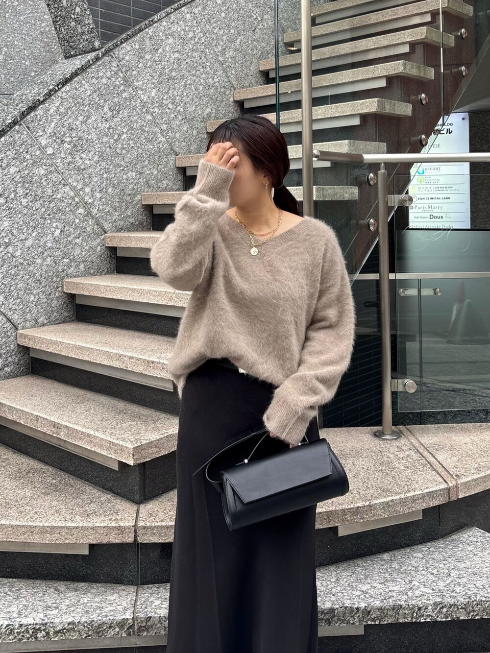 ブラック系のスカート、ブラック系のショルダーバッグ、ホワイト系のその他アウターを着用したレディースの冬コーディネートの3枚目の写真