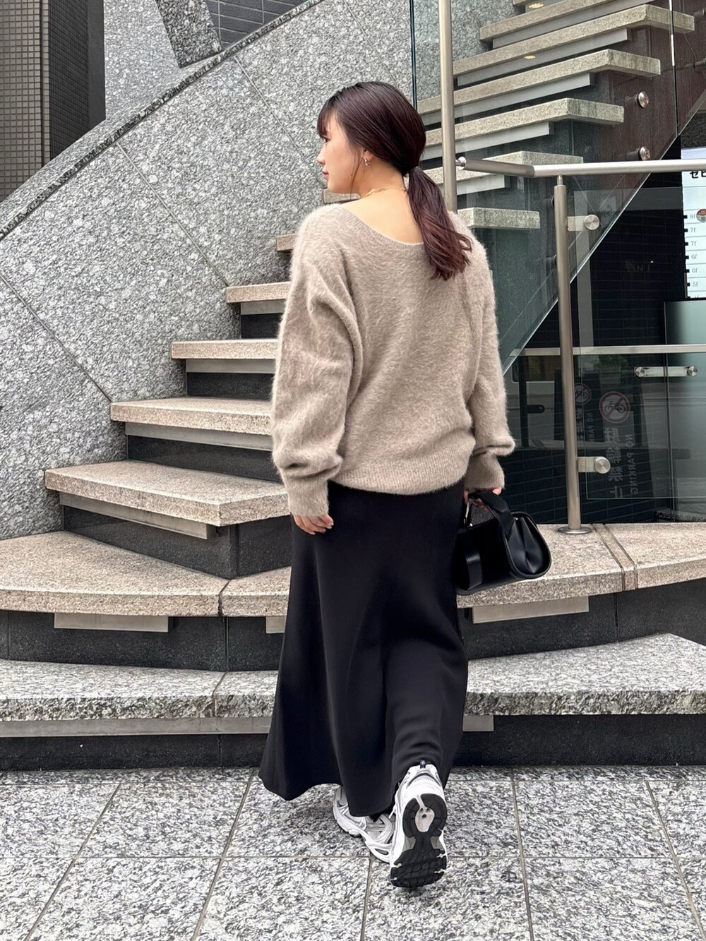 ブラック系のスカート、ブラック系のショルダーバッグ、ホワイト系のその他アウターを着用したレディースの冬コーディネートの2枚目の写真