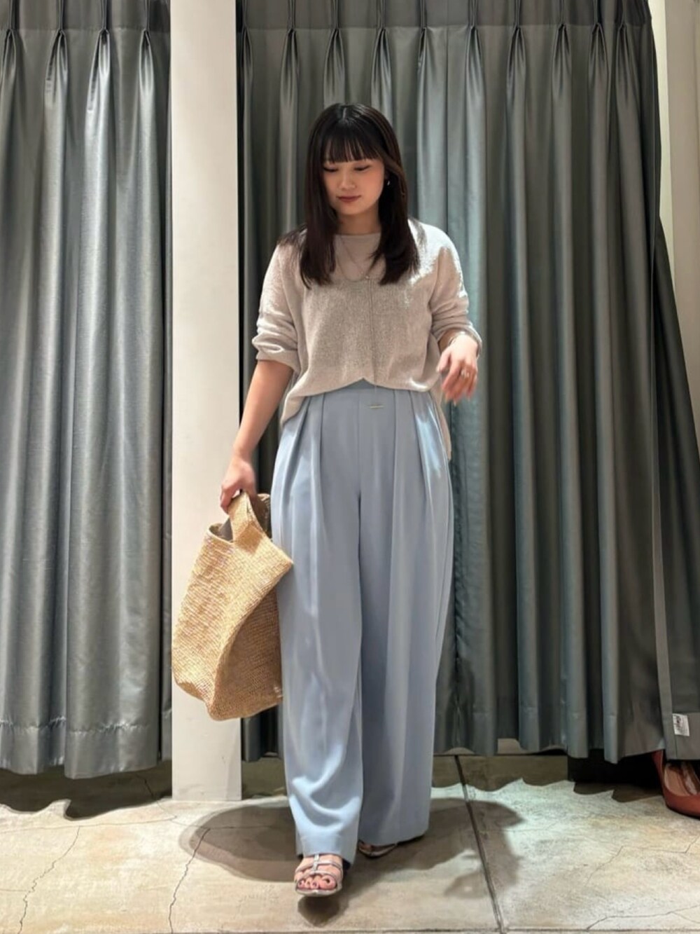 ブラック系のスラックス、グレー系のニット/セーター、ベージュ系のかごバッグを着用したレディースの夏コーディネートの3枚目の写真