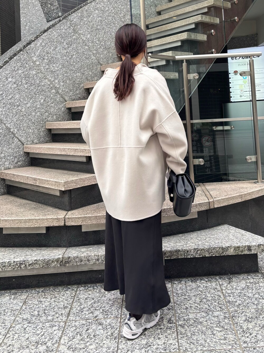 ブラック系のスカート、ブラック系のショルダーバッグ、ホワイト系のその他アウターを着用したレディースの冬コーディネートの5枚目の写真