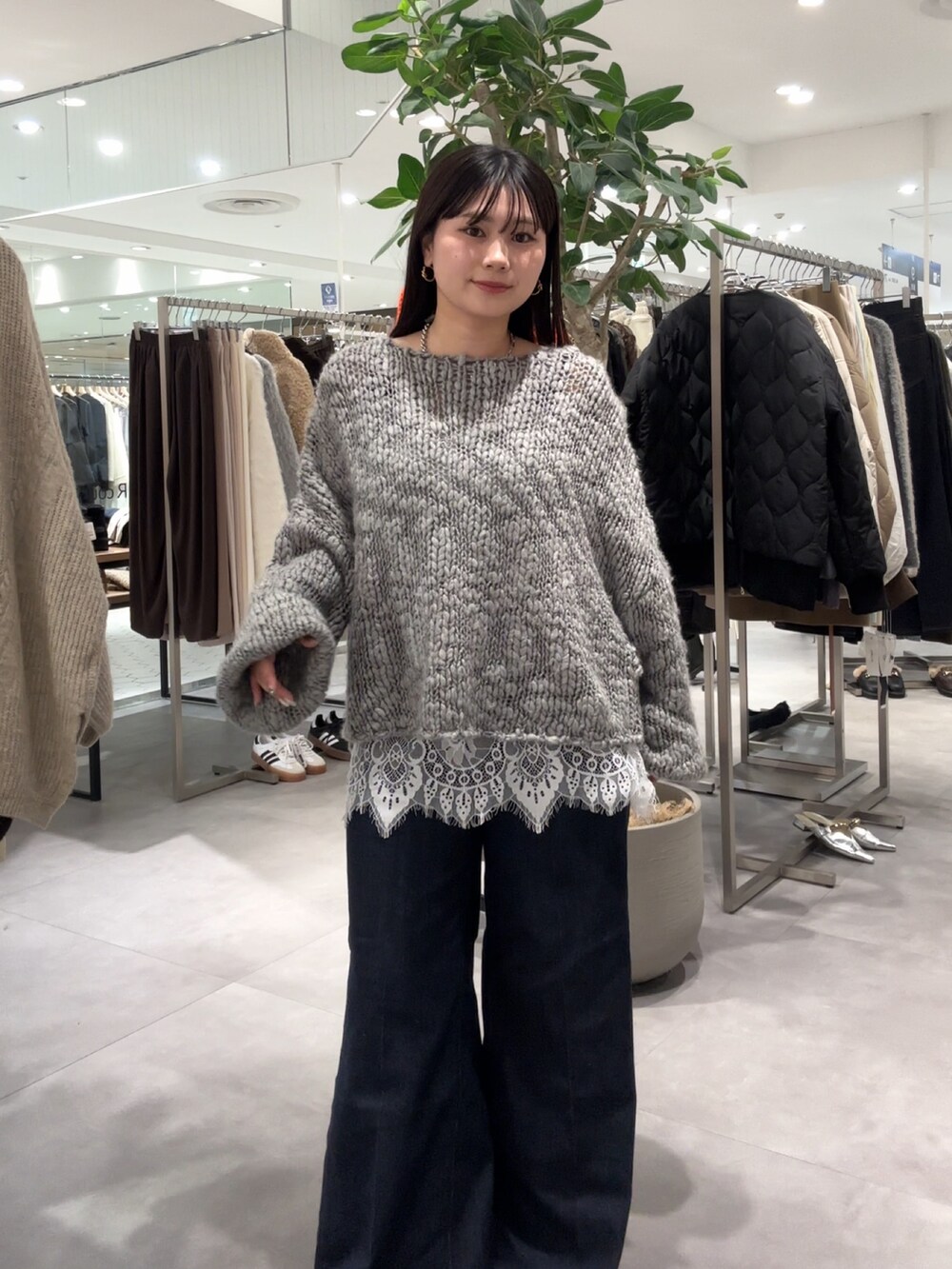 グレー系のニット/セーター、ブラウン系のパンプス、ホワイト系のシャツ/ブラウスを着用したレディースの冬コーディネートの2枚目の写真