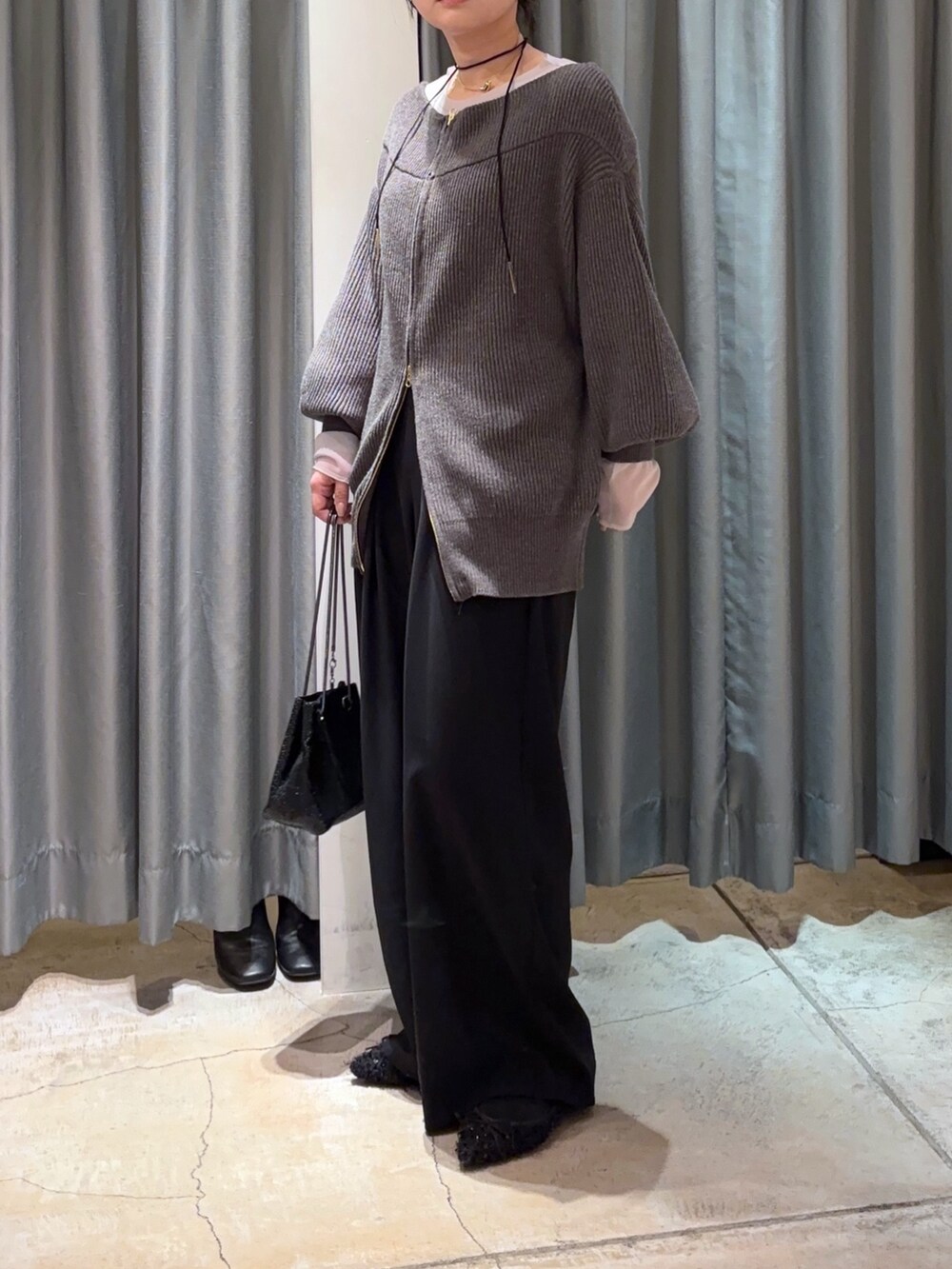 ブラック系のスラックス、グレー系のその他アウター、グレー系のニット/セーターを着用したレディースの冬コーディネートの3枚目の写真