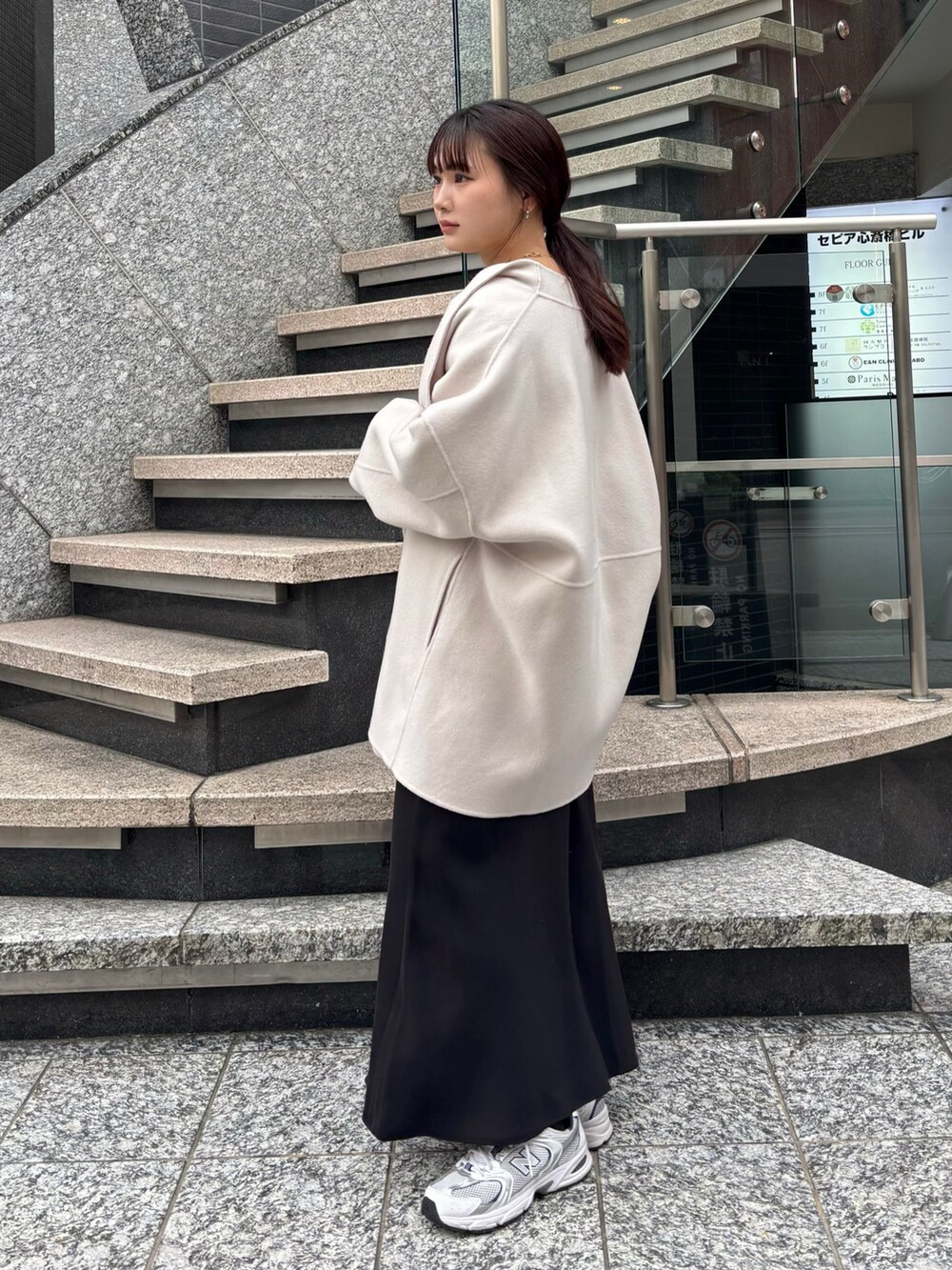 ブラック系のスカート、ブラック系のショルダーバッグ、ホワイト系のその他アウターを着用したレディースの冬コーディネートの4枚目の写真