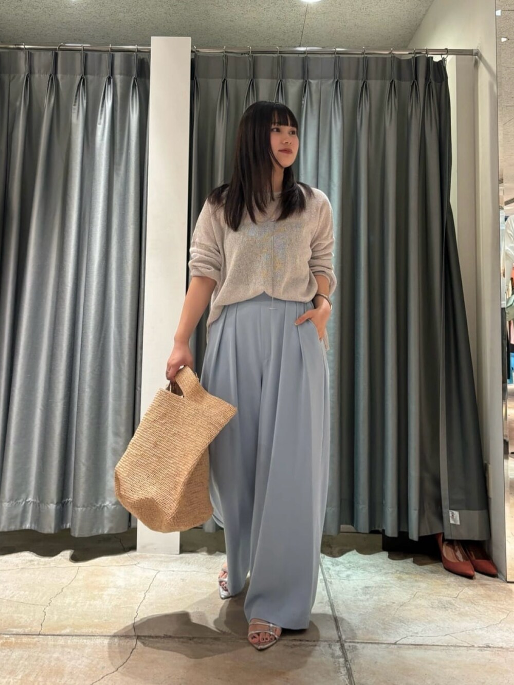 ブラック系のスラックス、グレー系のニット/セーター、ベージュ系のかごバッグを着用したレディースの夏コーディネートの2枚目の写真