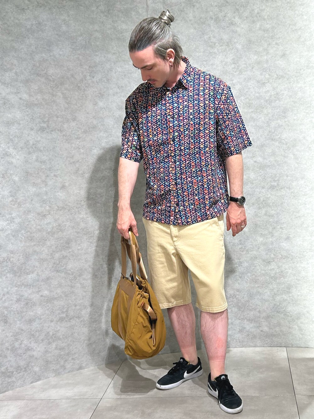 ブルー系のトップス、ホワイト系のパンツ、レッド系のバッグを着用したメンズの春コーディネートの2枚目の写真