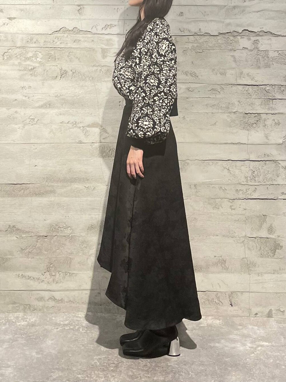 ブラック系のブーツ、ブラック系のニット/セーター、ブラック系のスカートを着用したレディースの秋コーディネートの2枚目の写真