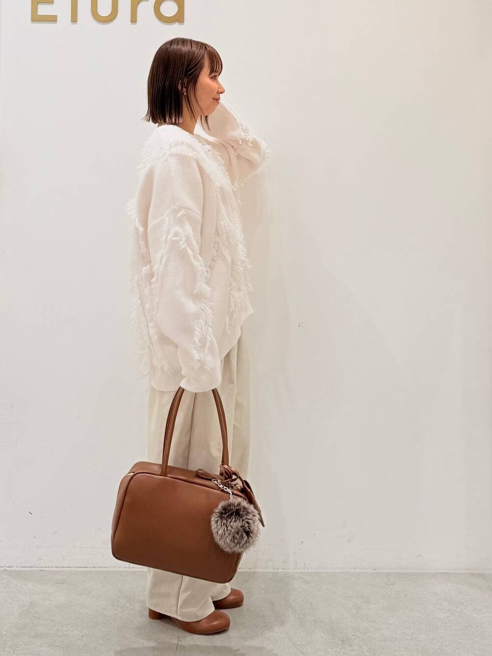 ブラウン系のブーツ、イエロー系のボストンバッグ、ホワイト系のその他パンツを着用したレディースの秋コーディネートの9枚目の写真