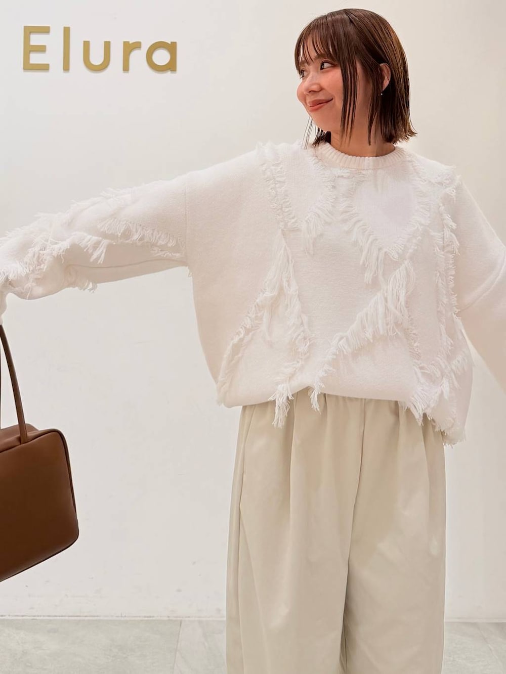 ブラウン系のブーツ、イエロー系のボストンバッグ、ホワイト系のその他パンツを着用したレディースの秋コーディネートの5枚目の写真