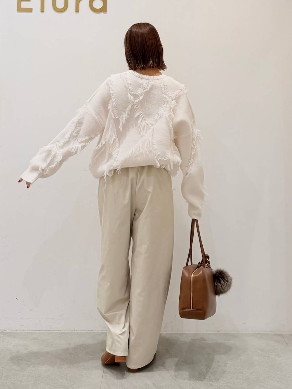 ブラウン系のブーツ、イエロー系のボストンバッグ、ホワイト系のその他パンツを着用したレディースの秋コーディネートの3枚目の写真