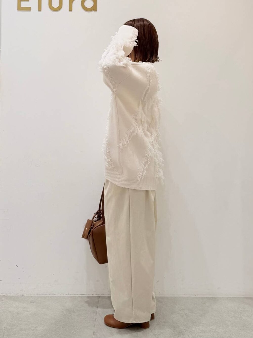 ブラウン系のブーツ、イエロー系のボストンバッグ、ホワイト系のその他パンツを着用したレディースの秋コーディネートの7枚目の写真