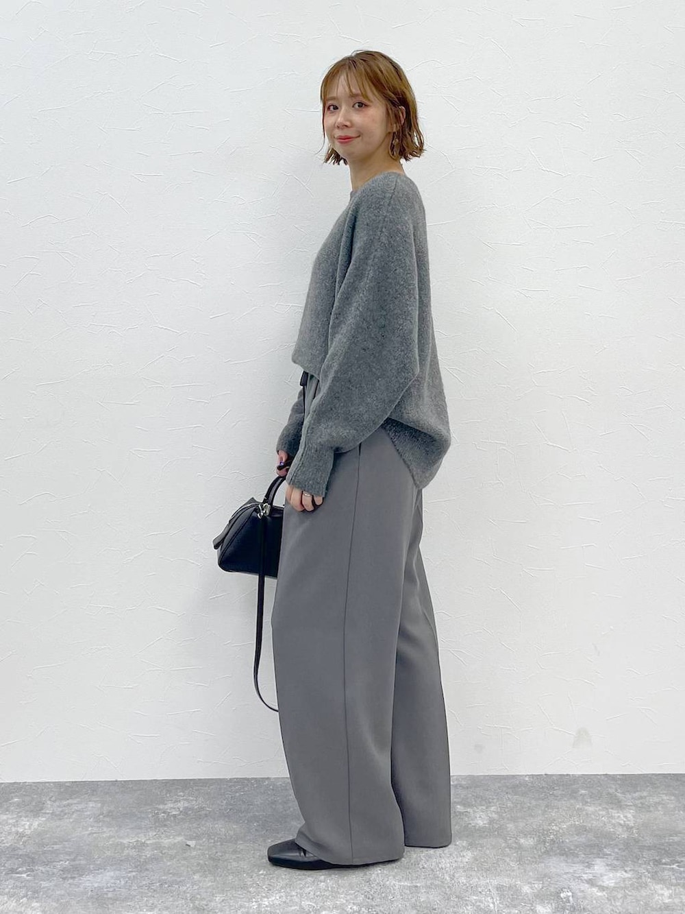 グレー系のその他パンツ、グレー系のニット/セーター、ブラック系のパンプスを着用したレディースの秋コーディネートの2枚目の写真