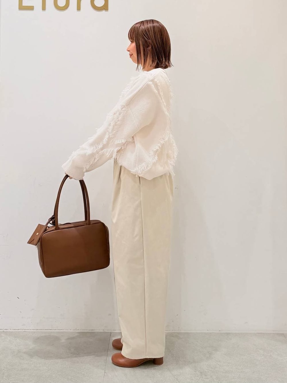 ブラウン系のブーツ、イエロー系のボストンバッグ、ホワイト系のその他パンツを着用したレディースの秋コーディネートの2枚目の写真