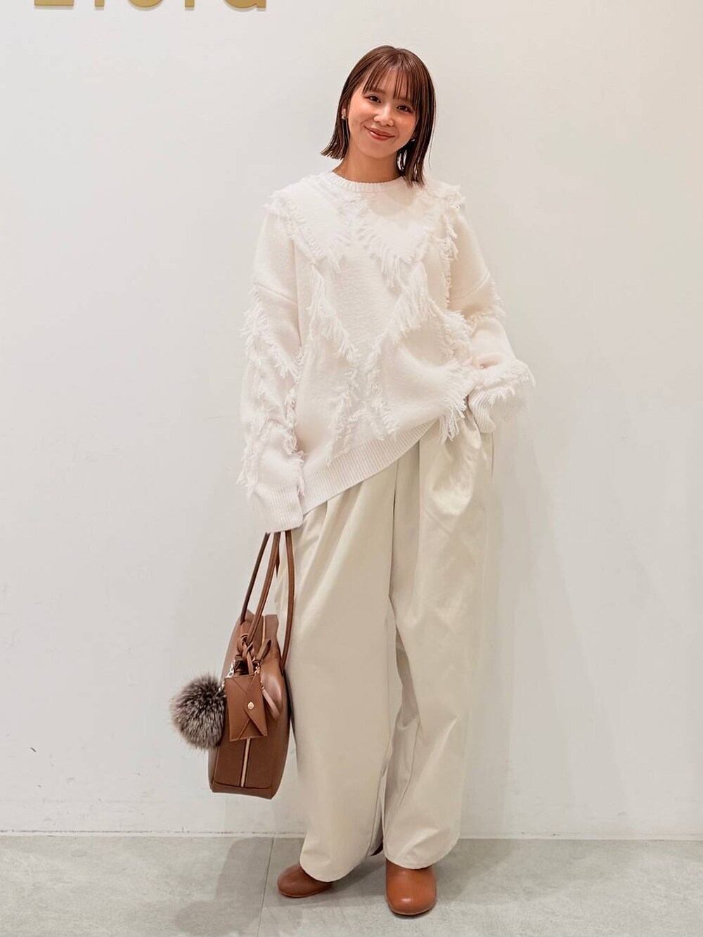 ブラウン系のブーツ、イエロー系のボストンバッグ、ホワイト系のその他パンツを着用したレディースの秋コーディネートの6枚目の写真