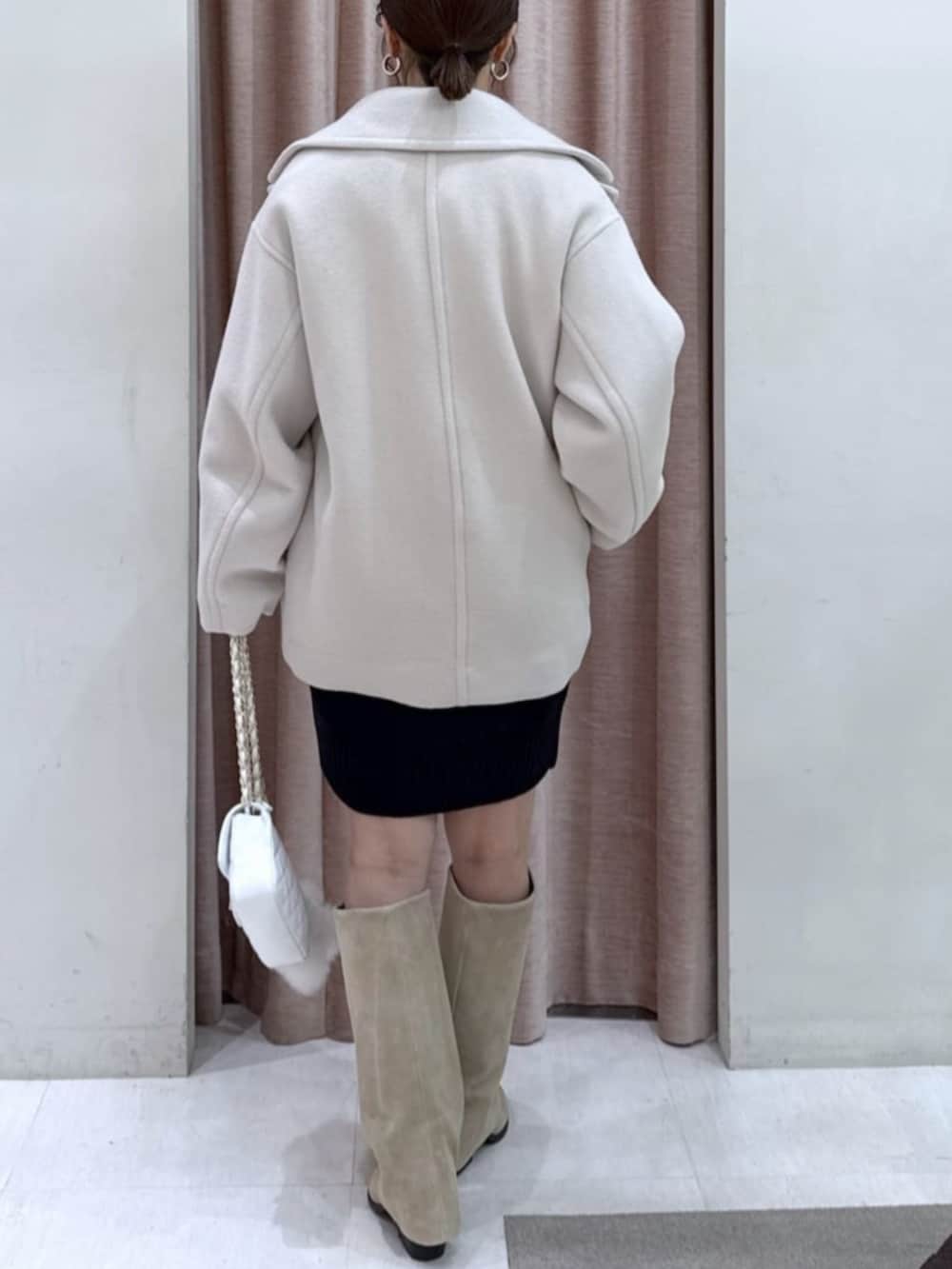 ホワイト系のトートバッグ、ブラック系のワンピース、ホワイト系のピーコートを着用したレディースの冬コーディネートの3枚目の写真