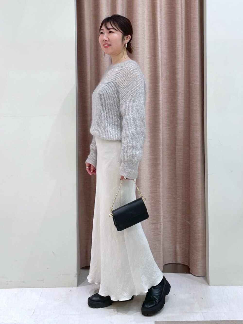 グレー系のスカート、シルバー系のニット/セーターを着用したレディースの秋コーディネートの2枚目の写真
