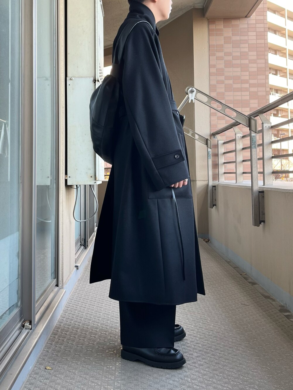 ブラック系のチェスターコート、ブラック系のスラックス、ブラック系のブーツを着用したメンズの冬コーディネートの2枚目の写真