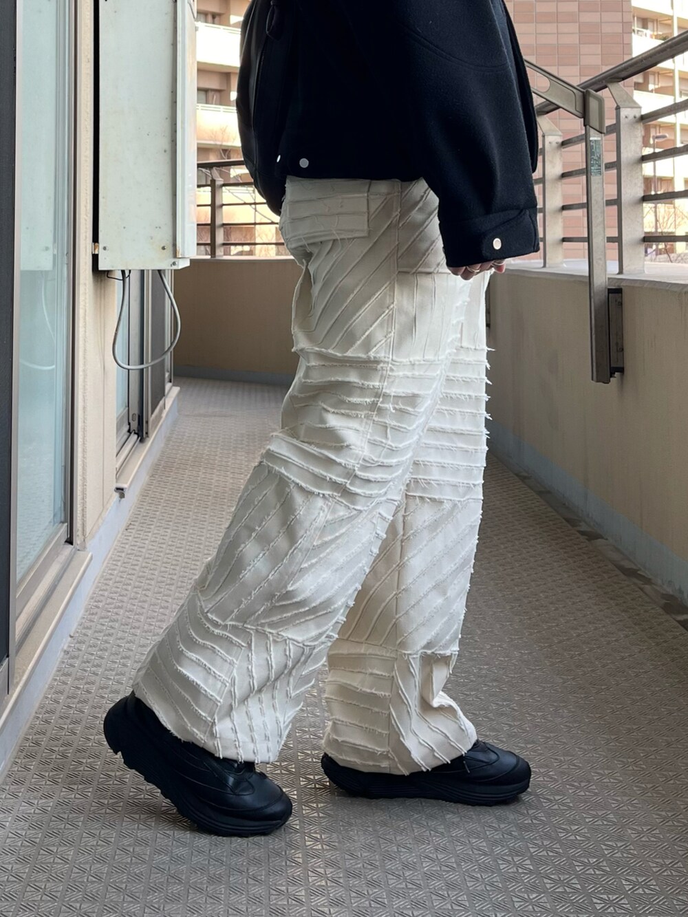 ブラック系のジャケット/アウター、ブラック系のショルダーバッグ、ホワイト系のパンツを着用したメンズの冬コーディネートの3枚目の写真