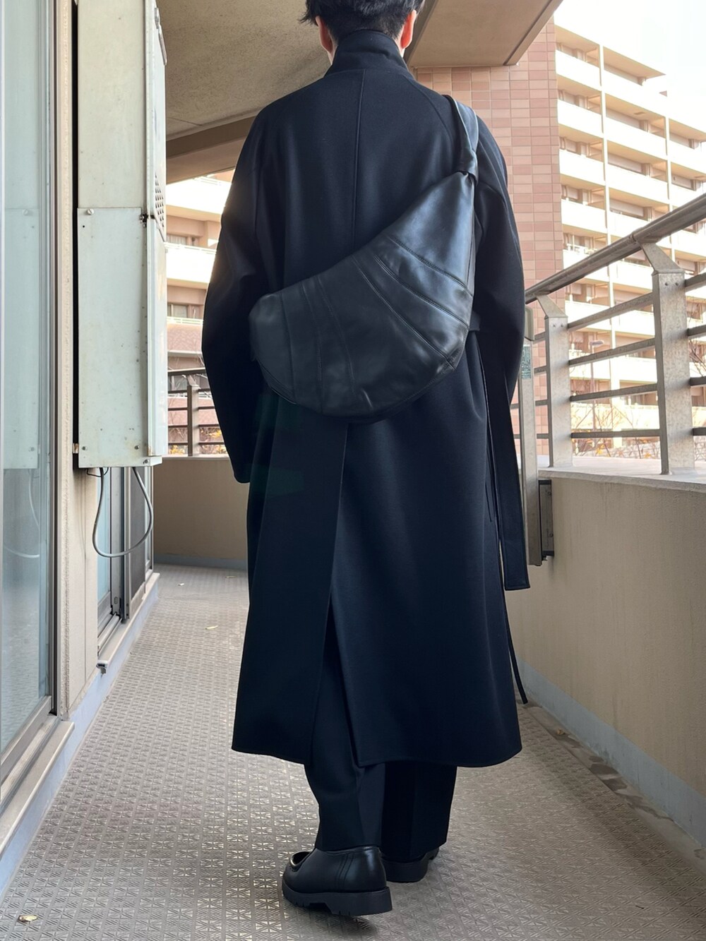 ブラック系のチェスターコート、ブラック系のスラックス、ブラック系のブーツを着用したメンズの冬コーディネートの3枚目の写真