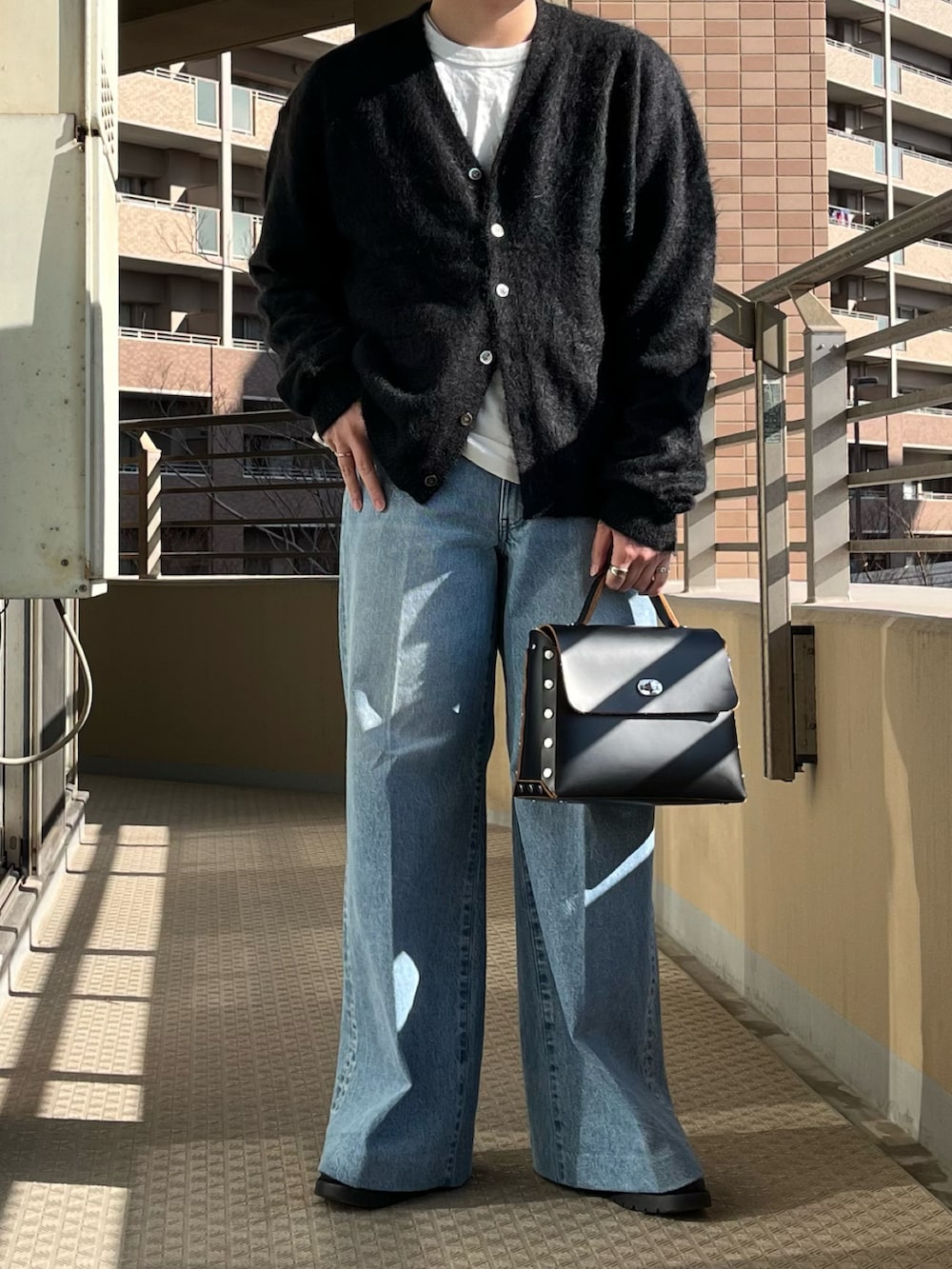 ブラック系のショルダーバッグ、ブルー系のデニムパンツ、ブラック系のカーディガン/ボレロを着用したメンズの冬コーディネートの5枚目の写真
