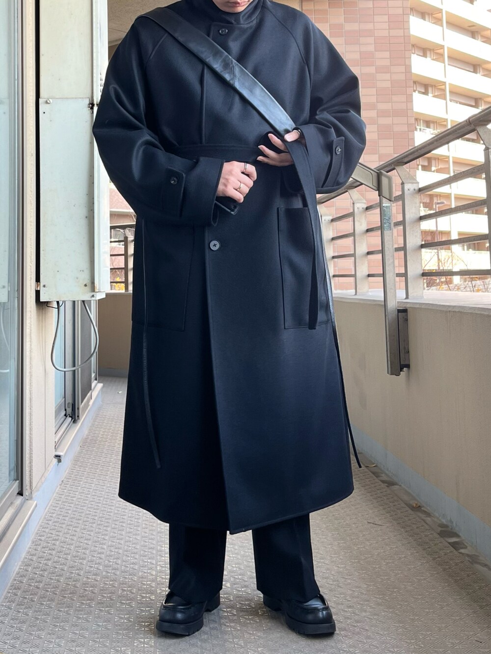 ブラック系のチェスターコート、ブラック系のスラックス、ブラック系のブーツを着用したメンズの冬コーディネートの4枚目の写真