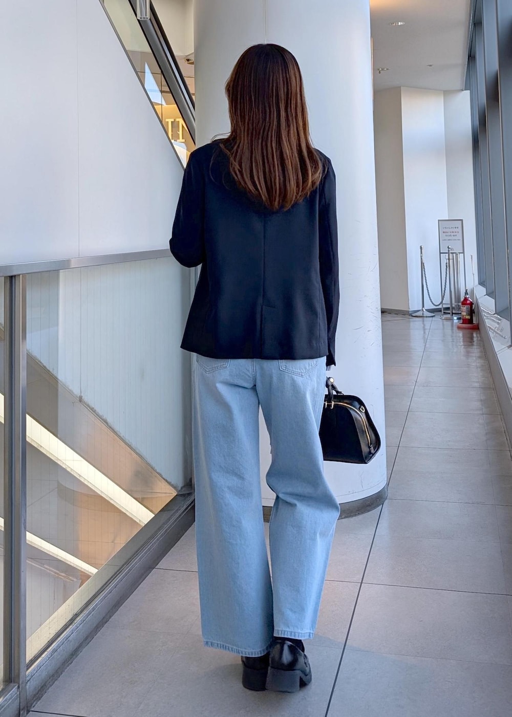 ブラック系のボストンバッグ、ブルー系のデニムパンツ、ブルー系のシャツ/ブラウスを着用したレディースの春コーディネートの5枚目の写真