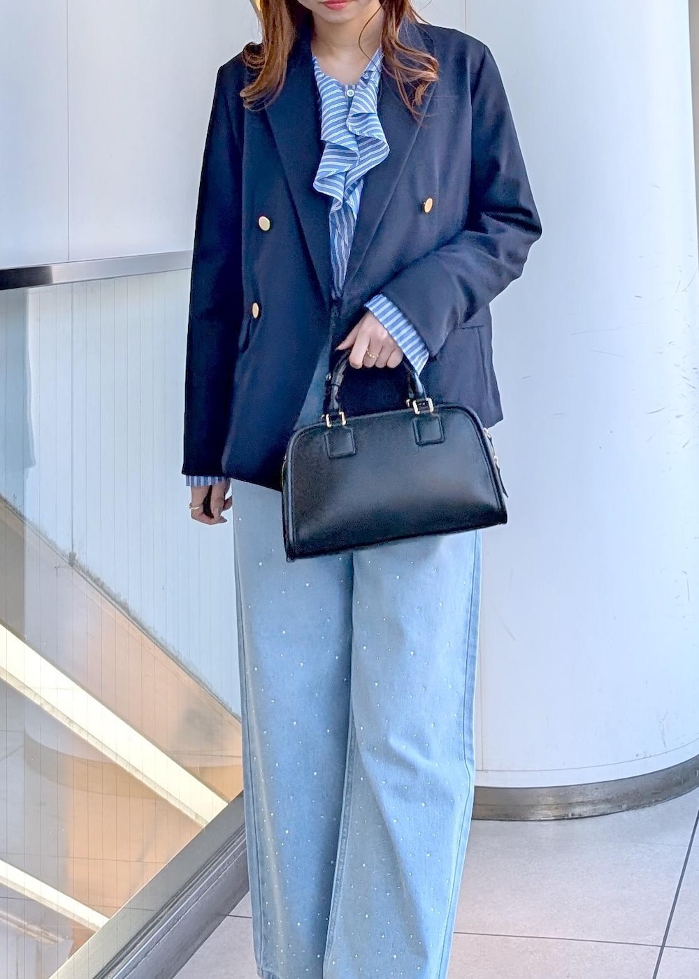 ブラック系のボストンバッグ、ブルー系のデニムパンツ、ブルー系のシャツ/ブラウスを着用したレディースの春コーディネートの3枚目の写真