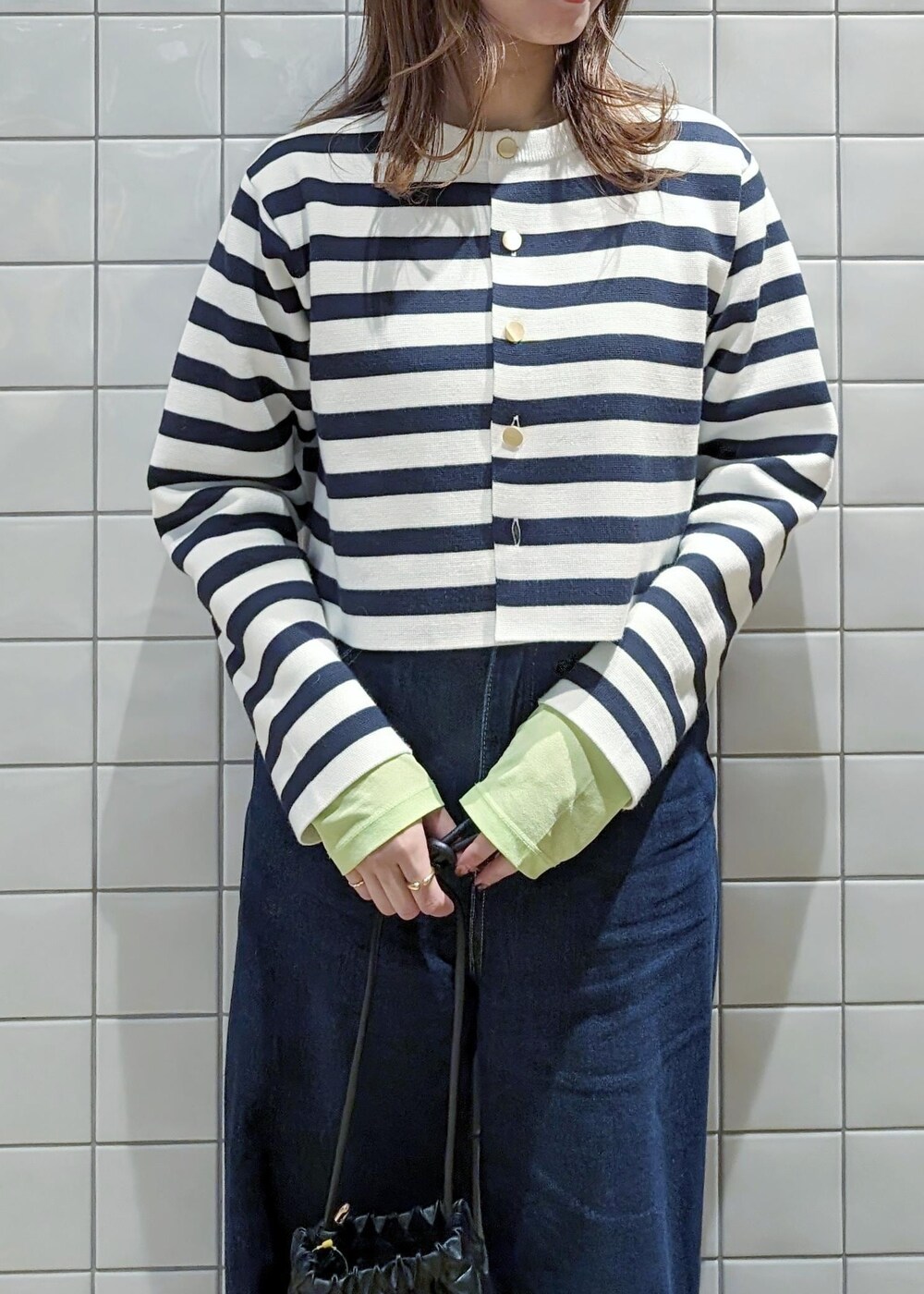 ホワイト系のカーディガン/ボレロ、グリーン系のTシャツ/カットソー、ブルー系のデニムパンツを着用したレディースの春コーディネートの2枚目の写真