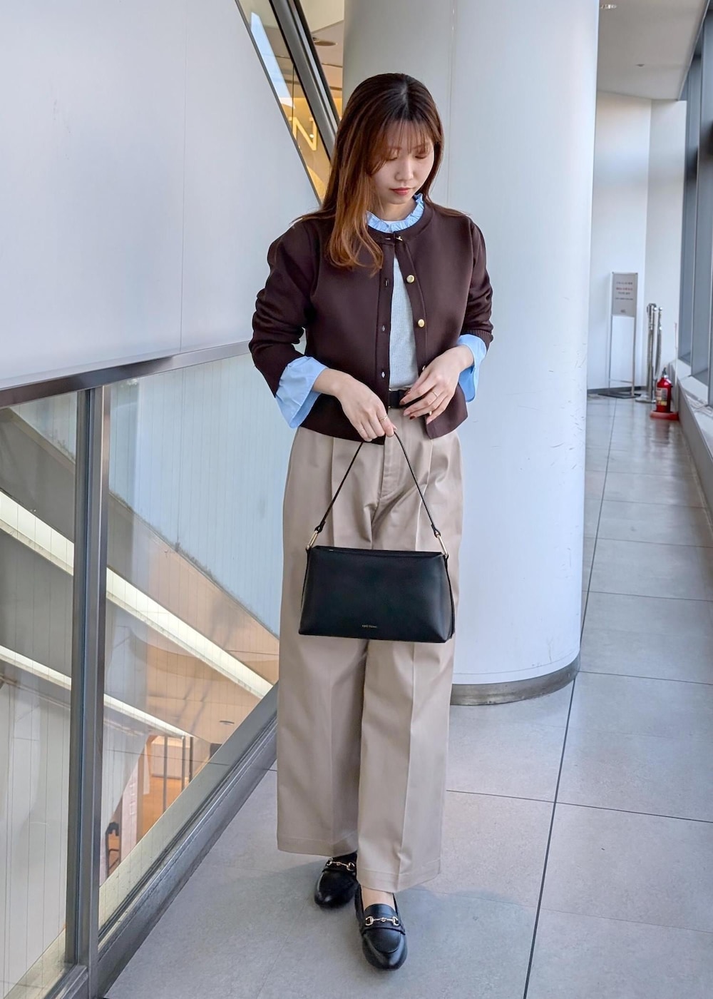 ブラック系のショルダーバッグ、ブラック系のローファー、ベージュ系のチノパンツを着用したレディースの冬コーディネートの2枚目の写真