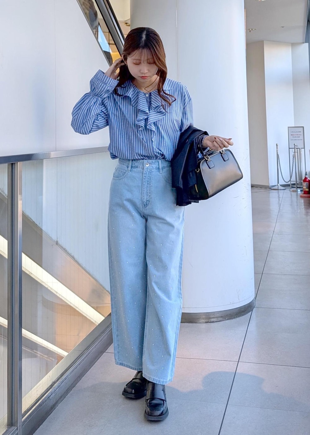 ブラック系のボストンバッグ、ブルー系のデニムパンツ、ブルー系のシャツ/ブラウスを着用したレディースの春コーディネートの7枚目の写真