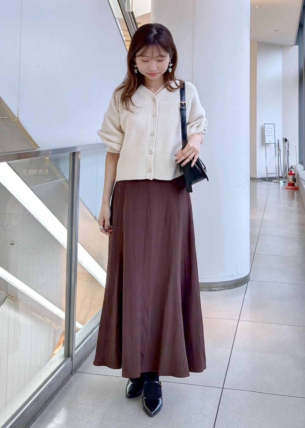 ブラック系のパンプス、ブラック系のショルダーバッグ、ホワイト系のカーディガン/ボレロを着用したレディースの秋コーディネートの6枚目の写真