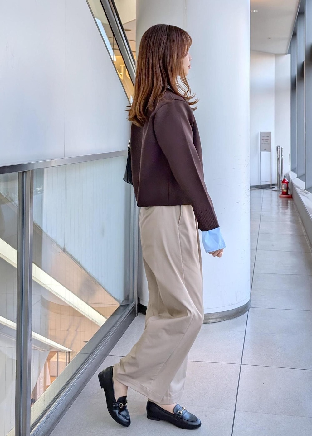 ブラック系のショルダーバッグ、ブラック系のローファー、ベージュ系のチノパンツを着用したレディースの冬コーディネートの6枚目の写真